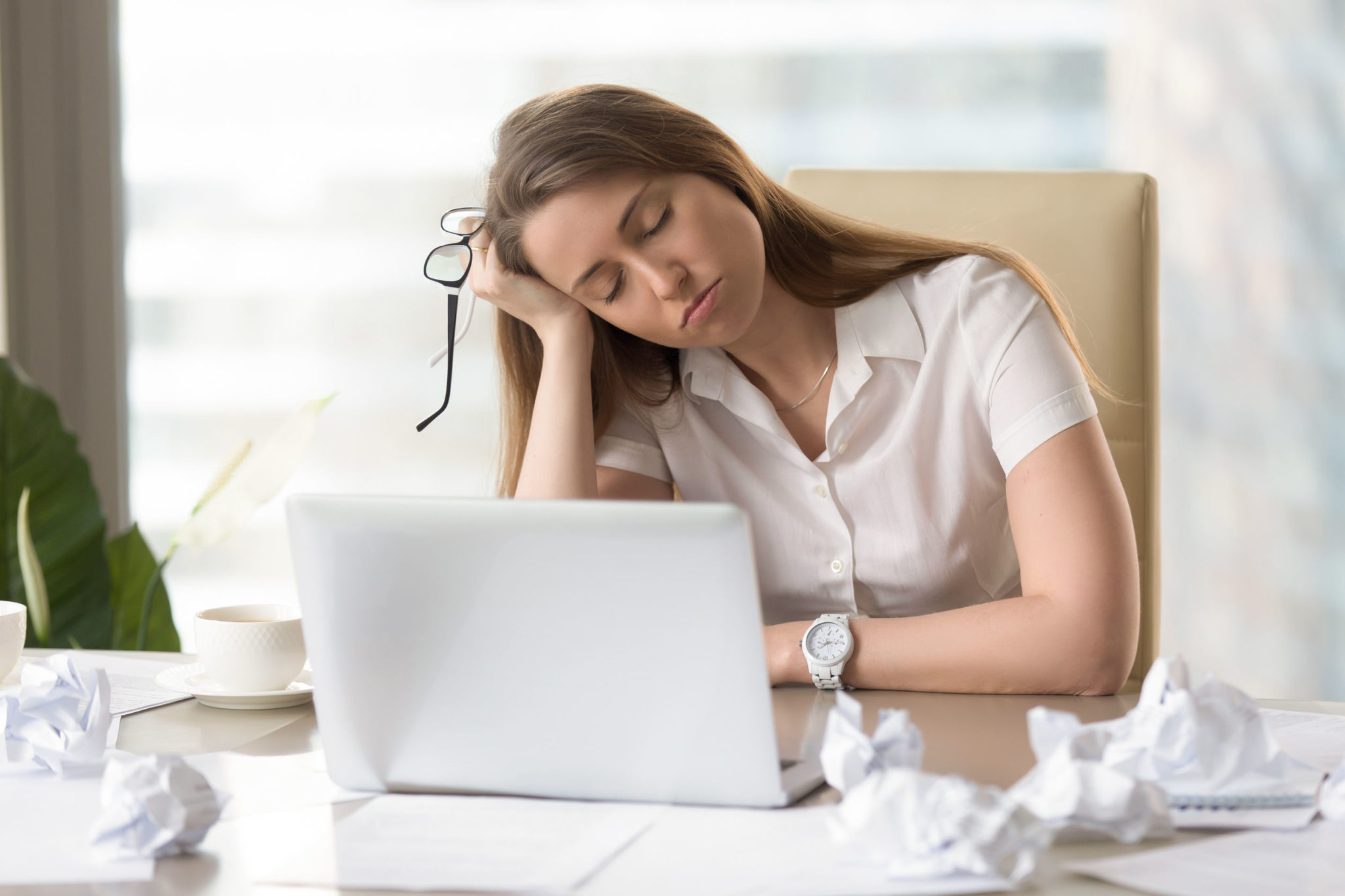 Businesswoman sleeping with head on hand at work